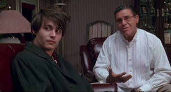 Movie still from “Arizona Dream” (1993), directed by Emir Kusturica – A man and a boy sitting next to each other in a room; Medium shot, Over the shoulder angle