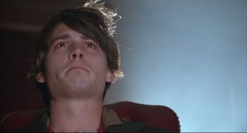 Movie still from “Arizona Dream” (1993), directed by Emir Kusturica – A young man sitting in a chair looking upward; Close Up shot, Low angle