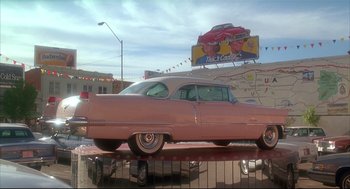 Movie still from “Arizona Dream” (1993), directed by Emir Kusturica – An old pink car parked in front of a billboard; Wide shot, Low angle