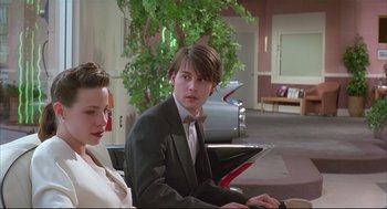 Movie still from “Arizona Dream” (1993), directed by Emir Kusturica – A man and a woman sitting next to each other in a room; Medium shot, Over the shoulder angle