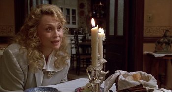 Movie still from “Arizona Dream” (1993), directed by Emir Kusturica – A woman sitting in front of a lit candle on top of a table; Close Up shot, Over the shoulder angle
