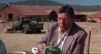 Movie still from “Arizona Dream” (1993), directed by Emir Kusturica – An older man sitting in front of a green teapot; Medium shot, Over the shoulder angle