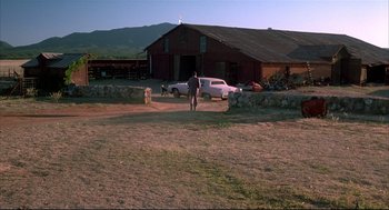 Movie still from “Arizona Dream” (1993), directed by Emir Kusturica – A man standing in a dirt field next to a white truck; Extreme Wide shot, Low angle
