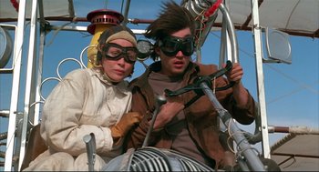 Movie still from “Arizona Dream” (1993), directed by Emir Kusturica – A man and a woman wearing goggles while sitting in a vehicle; Medium shot, Low angle