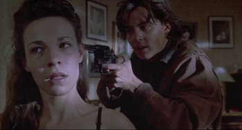 Movie still from “Arizona Dream” (1993), directed by Emir Kusturica – A man is holding a gun pointed at a woman's face; Close Up shot, Over the shoulder angle