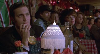 Movie still from “Arizona Dream” (1993), directed by Emir Kusturica – A group of people sitting at a table with a lamp; Close Up shot, Over the shoulder angle
