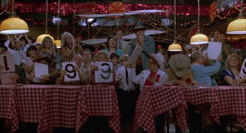 Movie still from “Arizona Dream” (1993), directed by Emir Kusturica – A group of people sitting at a table with numbers on them; Medium shot, High angle