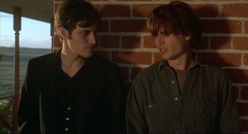 Movie still from “Arizona Dream” (1993), directed by Emir Kusturica – Two men standing next to each other in front of a brick wall; Close Up shot, Over the shoulder angle