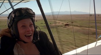 Movie still from “Arizona Dream” (1993), directed by Emir Kusturica – A woman smiles while sitting in an airplane; Close Up shot, Low angle