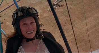 Movie still from “Arizona Dream” (1993), directed by Emir Kusturica – A woman wearing a helmet while standing on top of a hill; Close Up shot, Overhead angle