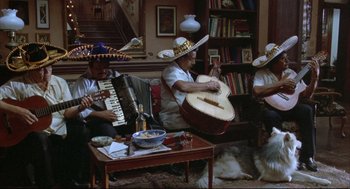 Movie still from “Arizona Dream” (1993), directed by Emir Kusturica – A group of men sitting around a living room playing musical instruments; Wide shot, High angle