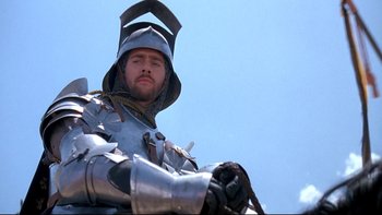 Movie still from “Army of Darkness” (1992), directed by Sam Raimi – A man wearing a suit of armor and a helmet; Medium shot, Low angle