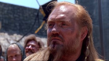 Movie still from “Army of Darkness” (1992), directed by Sam Raimi – A man with long hair and a long beard; Close Up shot, Low angle