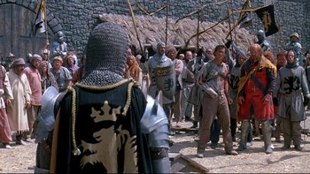 Movie still from “Army of Darkness” (1992), directed by Sam Raimi – A group of people dressed in medieval costumes; Wide shot, Over the shoulder angle