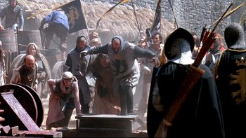 Movie still from “Army of Darkness” (1992), directed by Sam Raimi – A group of people dressed in medieval clothing; Wide shot, Low angle