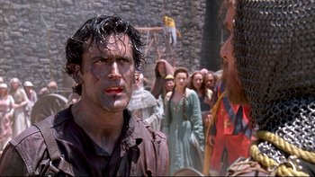 Movie still from “Army of Darkness” (1992), directed by Sam Raimi – A group of people standing in front of a wall; Close Up shot, Over the shoulder angle