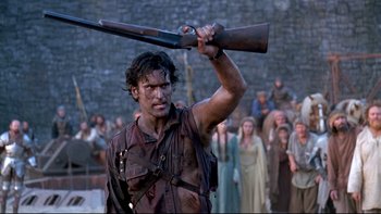 Movie still from “Army of Darkness” (1992), directed by Sam Raimi – A man holding a rifle over his head in front of a group of people; Medium shot, Low angle