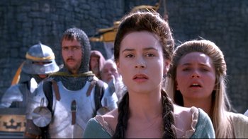 Movie still from “Army of Darkness” (1992), directed by Sam Raimi – A group of people standing in front of a stone wall; Close Up shot, Over the shoulder angle