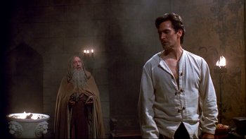 Movie still from “Army of Darkness” (1992), directed by Sam Raimi – A man standing next to another man in a room; Medium shot, Over the shoulder angle