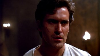 Movie still from “Army of Darkness” (1992), directed by Sam Raimi – A person wearing a white t - shirt; Close Up shot, Low angle