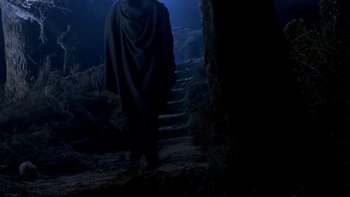 Movie still from “Army of Darkness” (1992), directed by Sam Raimi – A man in a black robe standing in a dark cave; Wide shot, Low angle