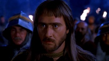 Movie still from “Army of Darkness” (1992), directed by Sam Raimi – A person with long hair and a beard; Close Up shot, Over the shoulder angle