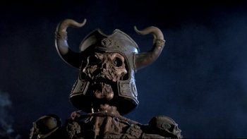 Movie still from “Army of Darkness” (1992), directed by Sam Raimi – The face of a statue wearing a horned helmet; Close Up shot, Low angle