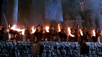 Movie still from “Army of Darkness” (1992), directed by Sam Raimi – A group of men in medieval garb holding torches; Wide shot, Low angle
