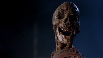 Movie still from “Army of Darkness” (1992), directed by Sam Raimi – A creepy looking skeleton is standing in the dark; Close Up shot, Low angle