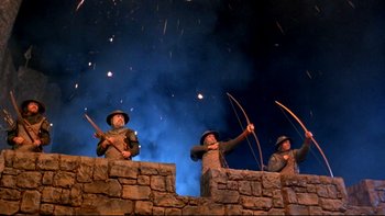 Movie still from “Army of Darkness” (1992), directed by Sam Raimi – A group of men standing next to each other holding arrows; Wide shot, Low angle