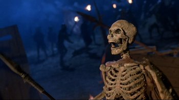 Movie still from “Army of Darkness” (1992), directed by Sam Raimi – A skeleton that is standing in front of some people; Medium shot, High angle