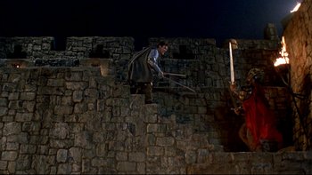A man riding a bike down the side of a brick wall