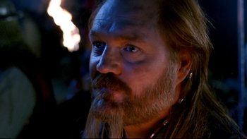 Movie still from “Army of Darkness” (1992), directed by Sam Raimi – A person with long hair and a beard; Close Up shot, Over the shoulder angle