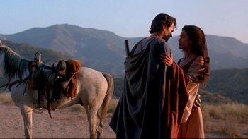 Movie still from “Army of Darkness” (1992), directed by Sam Raimi – A man and a woman standing next to a horse; Medium shot, Low angle