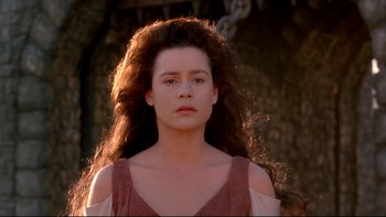 Movie still from “Army of Darkness” (1992), directed by Sam Raimi – A woman with long hair is standing in front of a tree; Close Up shot, Over the shoulder angle