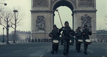 Movie still from “Army of Shadows” (1969), directed by Jean-Pierre Melville – A group of men marching down a street; Wide shot, Low angle