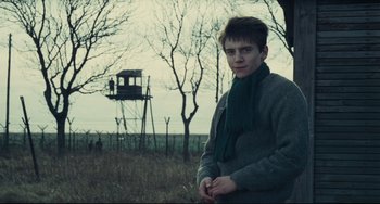 Movie still from “Army of Shadows” (1969), directed by Jean-Pierre Melville – A young man standing in a field near a tree; Medium shot, Low angle