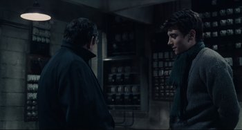 Movie still from “Army of Shadows” (1969), directed by Jean-Pierre Melville – Two men are standing next to each other in a dark room; Medium shot, Over the shoulder angle