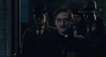 Movie still from “Army of Shadows” (1969), directed by Jean-Pierre Melville – A group of men standing next to each other in a dark room; Close Up shot, Over the shoulder angle