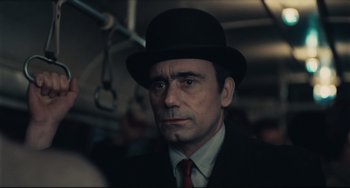 Movie still from “Army of Shadows” (1969), directed by Jean-Pierre Melville – A man in a suit and a hat on a bus; Close Up shot, Over the shoulder angle