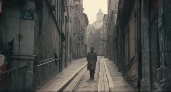 Movie still from “Army of Shadows” (1969), directed by Jean-Pierre Melville – A man is walking down a narrow alley way; Wide shot, High angle