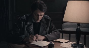 Movie still from “Army of Shadows” (1969), directed by Jean-Pierre Melville – A man sitting at a table writing in a notebook; Medium shot, High angle