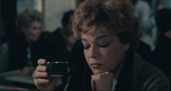 Movie still from “Army of Shadows” (1969), directed by Jean-Pierre Melville – A woman looking at a cell phone while sitting at a table; Close Up shot, High angle
