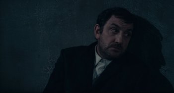 Movie still from “Army of Shadows” (1969), directed by Jean-Pierre Melville – A man in a black suit and white shirt looking up; Close Up shot, High angle