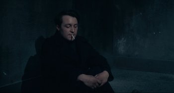 Movie still from “Army of Shadows” (1969), directed by Jean-Pierre Melville – A man sitting down with a cigarette in his mouth; Medium shot, High angle