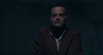 Movie still from “Army of Shadows” (1969), directed by Jean-Pierre Melville – A man wearing a brown jacket and a white shirt; Close Up shot, Low angle