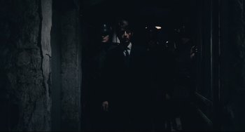 Movie still from “Army of Shadows” (1969), directed by Jean-Pierre Melville – A group of men standing next to each other in a dark room; Wide shot, High angle