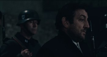 Movie still from “Army of Shadows” (1969), directed by Jean-Pierre Melville – A man in a black suit and a man in a black suit and a helmet; Close Up shot, Over the shoulder angle