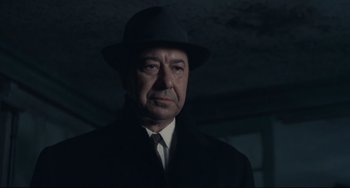 Movie still from “Army of Shadows” (1969), directed by Jean-Pierre Melville – An older man wearing a hat and a suit; Close Up shot, Low angle