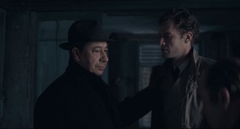 Movie still from “Army of Shadows” (1969), directed by Jean-Pierre Melville – A man in a hat and a man in a suit and tie; Medium shot, Over the shoulder angle